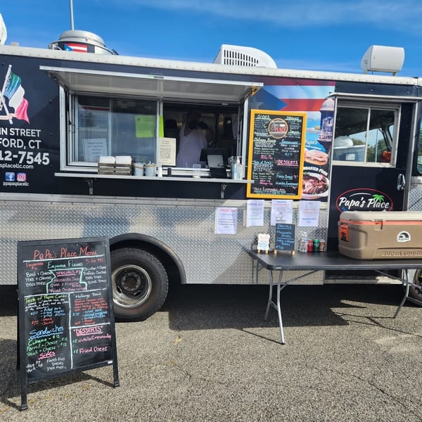 Papa’s Place food truck with open service window, colorful menu boards, outdoor cooler, and a sunny parking-lot setting.